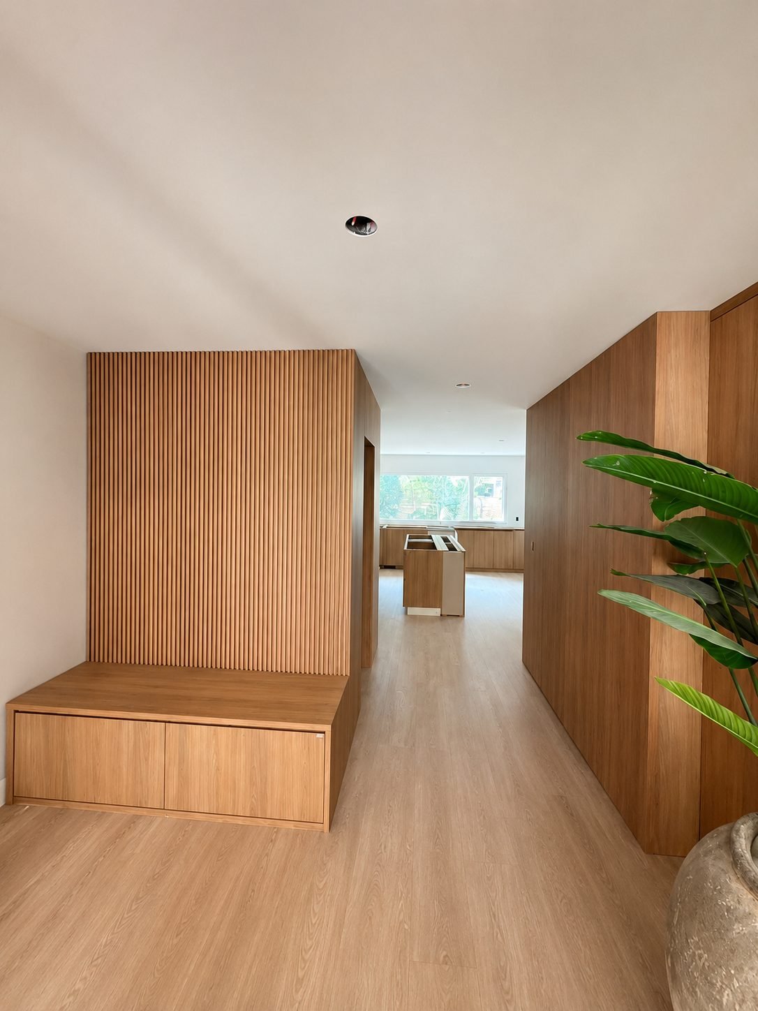 Entry bench with a slatted wood accent wall in a foyer leading to the kitchen