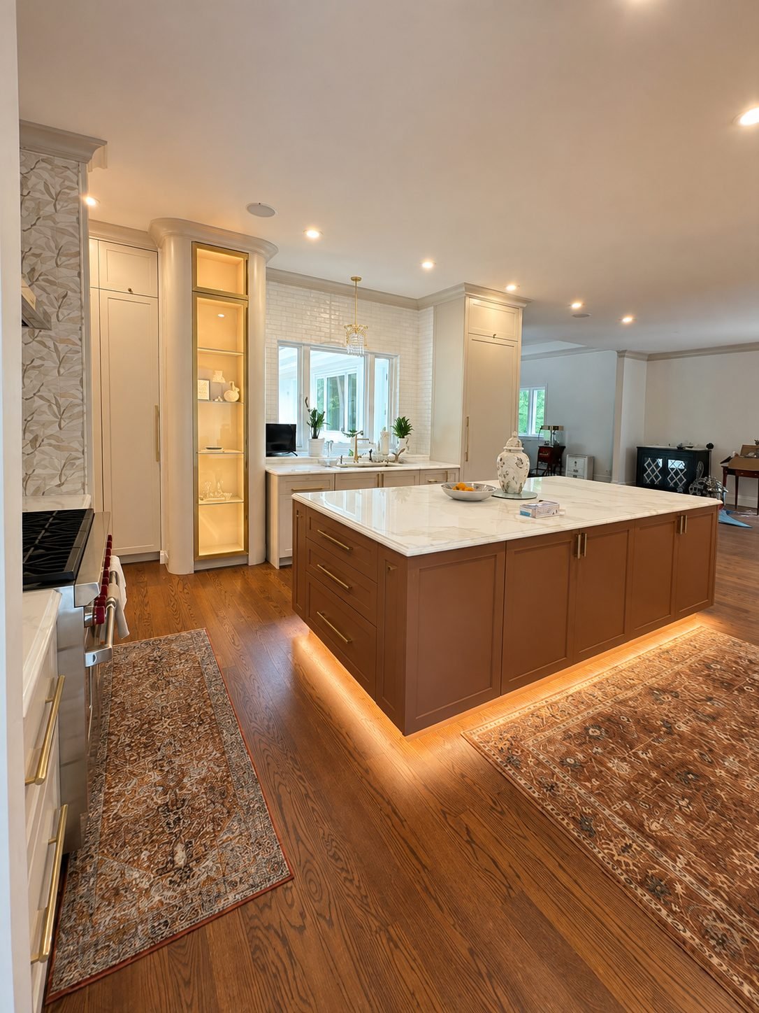 Kitchen with rust-terracotta island, marble countertop, floral wallpaper accent wall and an illuminated glass display niche