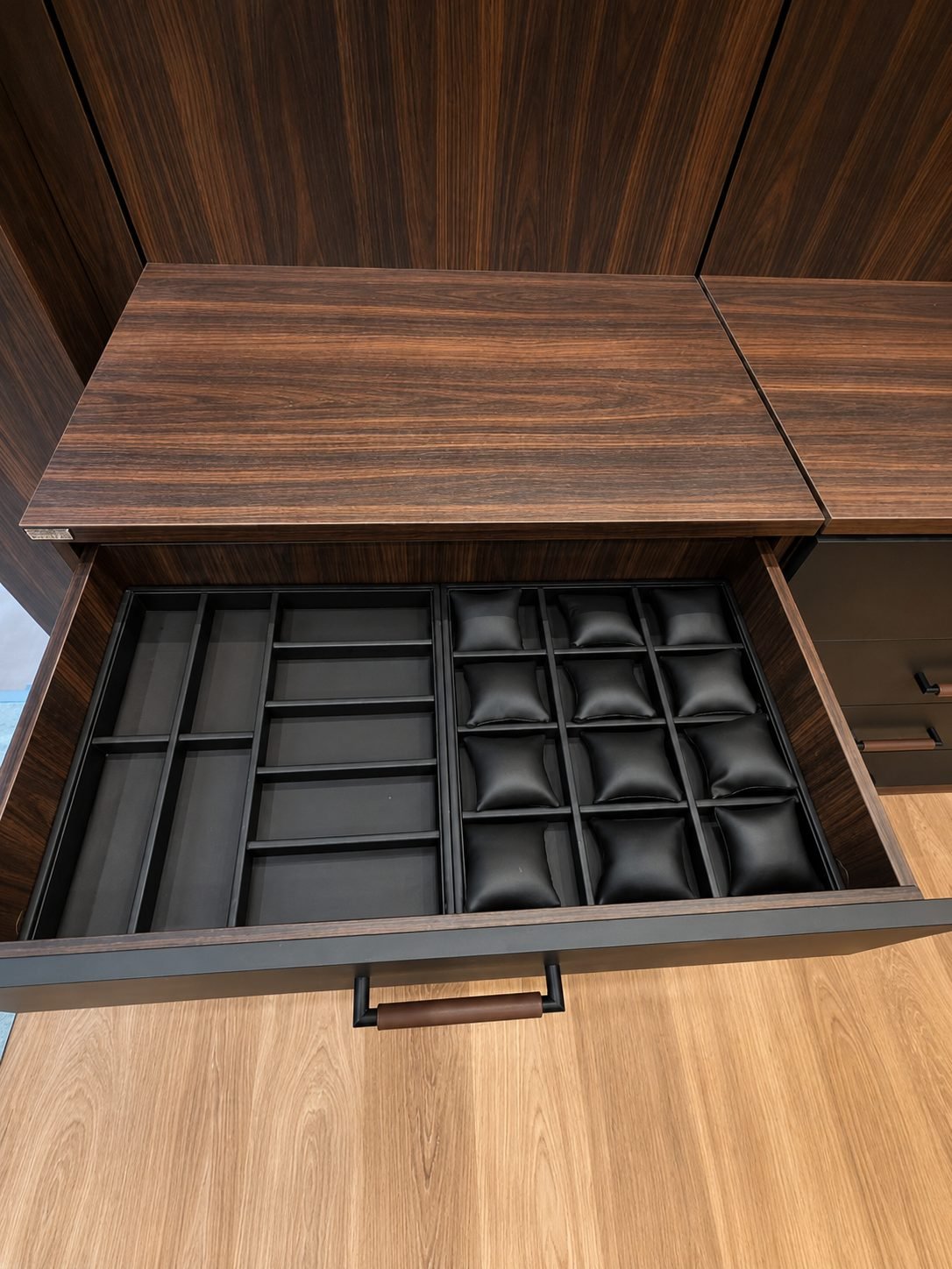 Open walnut drawer with padded leather watch pillows and wire dividers