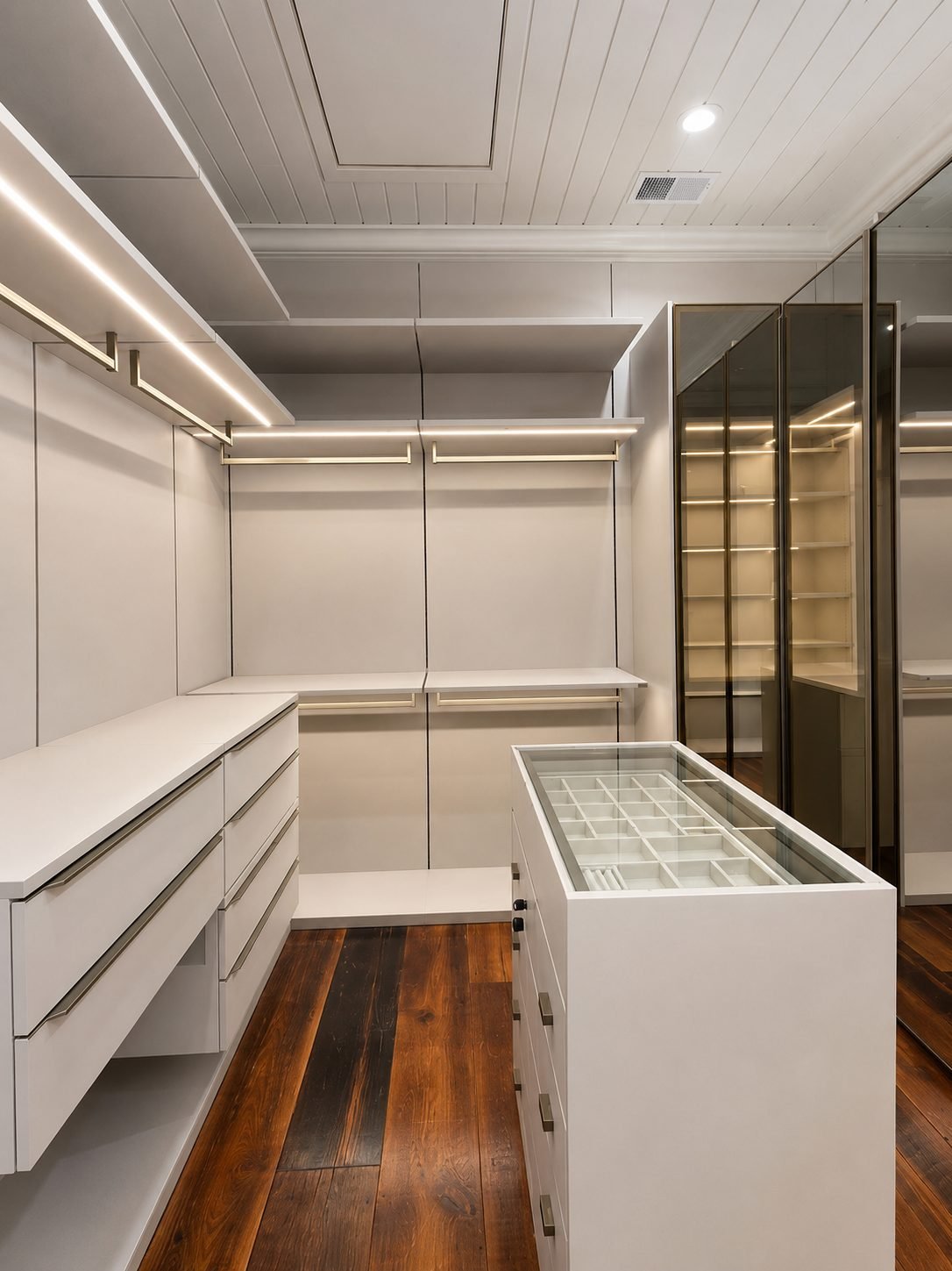 White lacquer dressing room with an open glass-top jewelry drawer, smoke mirror wardrobe and dark reclaimed wood floor