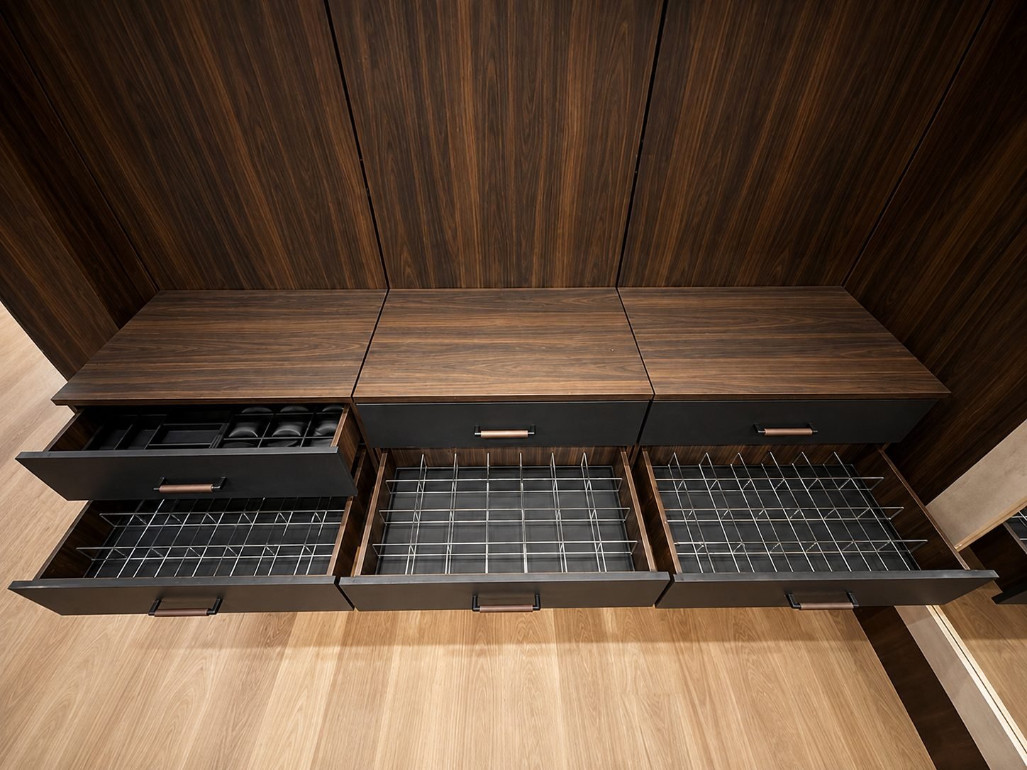 Open walnut drawers with wire grid dividers and a padded watch compartment